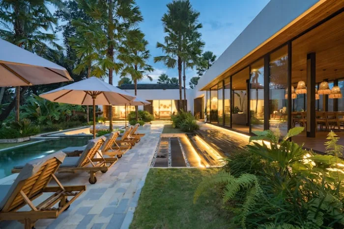 The villa lit up in the evening beside the pool